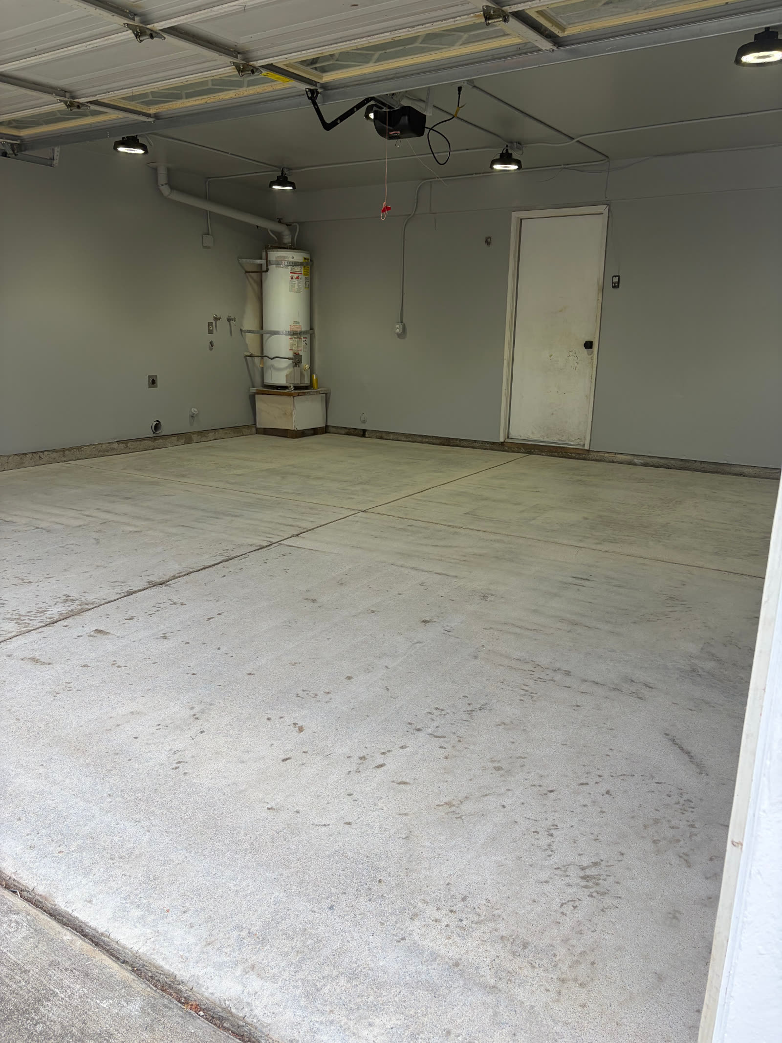 Empty two-car garage with stained bare concrete floor before coating