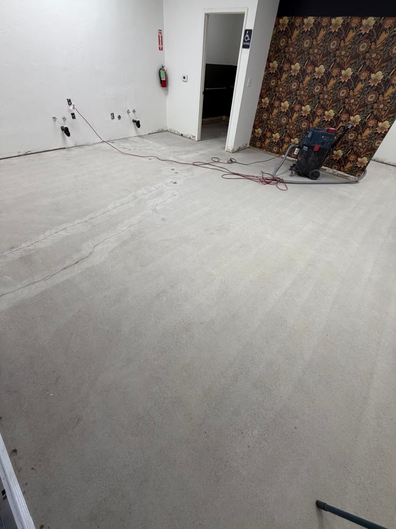 Commercial room with bare ground concrete floor and HEPA vacuum staged