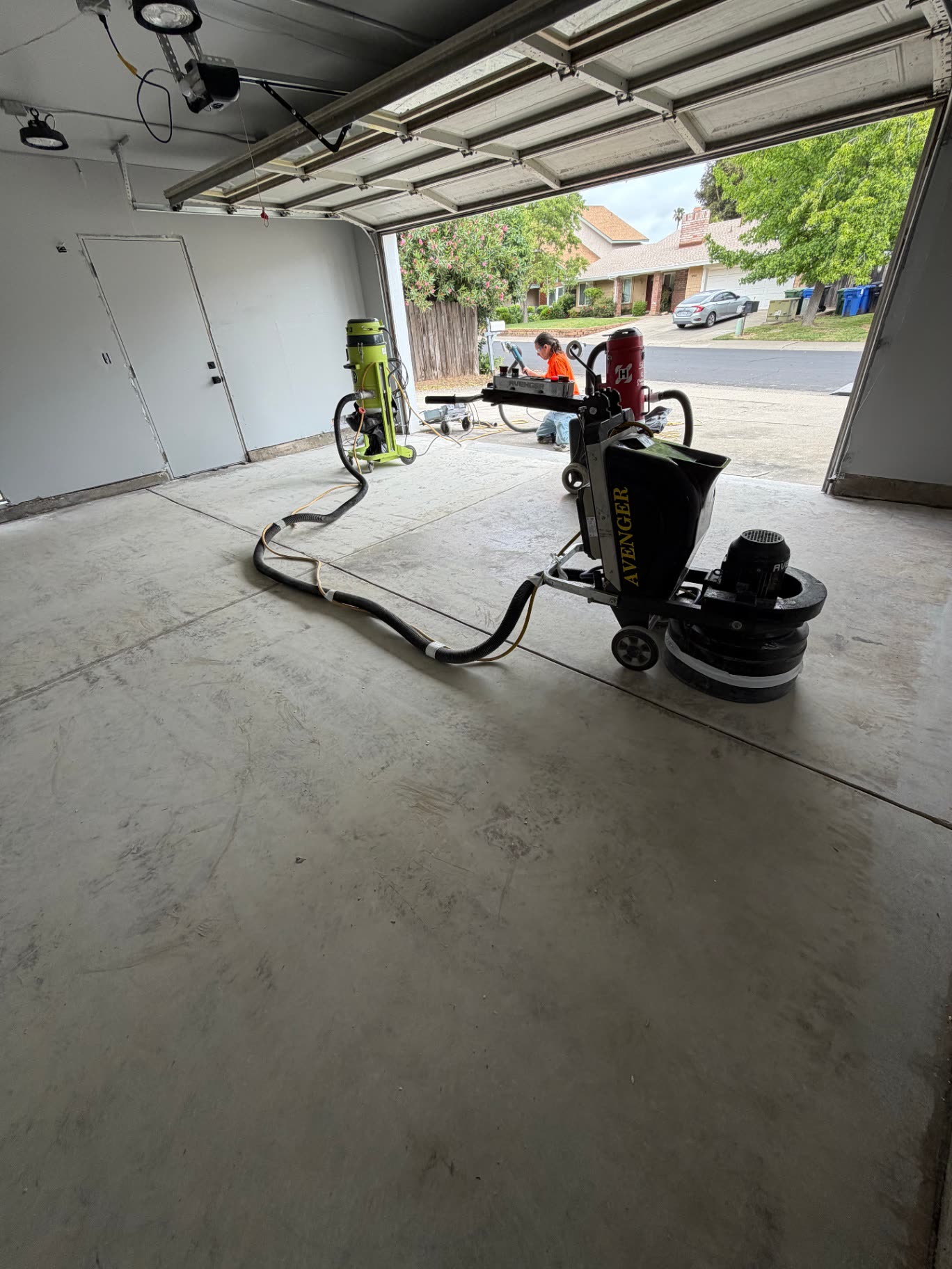 Diamond grinder and dust extractor prepping a garage slab for epoxy